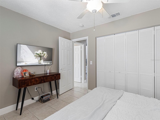 tiled bedroom featuring a closet, a textured ceiling, and ceiling fan