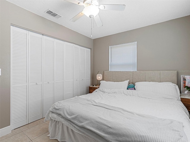 bedroom with baseboards, a closet, light tile patterned floors, a ceiling fan, and visible vents