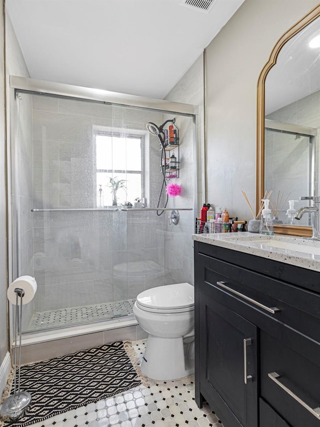 bathroom featuring visible vents, toilet, a shower stall, and vanity