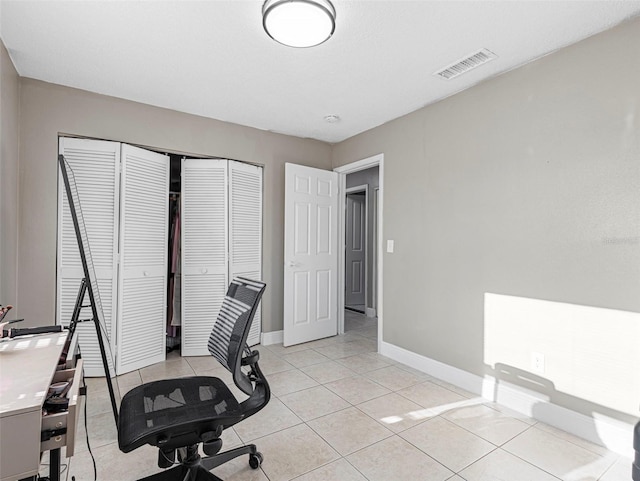 unfurnished office with light tile patterned floors, visible vents, and baseboards