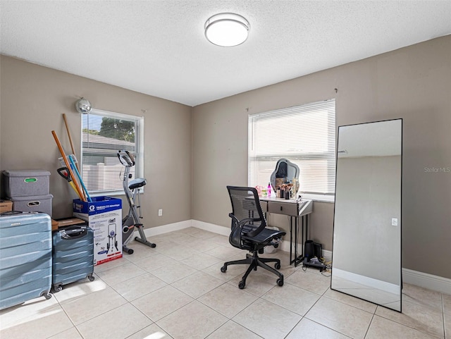 office with light tile patterned floors, a textured ceiling, and baseboards
