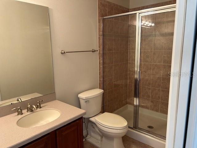 bathroom featuring toilet, vanity, and a shower with shower door