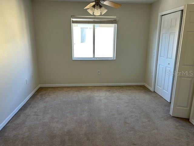 carpeted spare room featuring ceiling fan