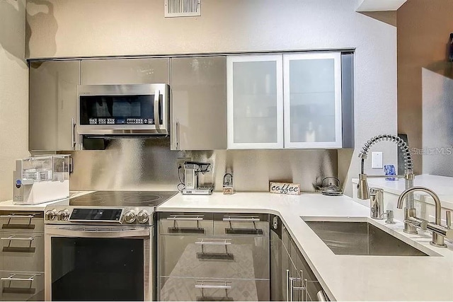 kitchen with appliances with stainless steel finishes, tasteful backsplash, and sink