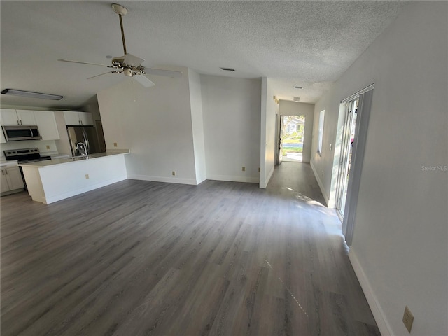 unfurnished living room featuring a textured ceiling, ceiling fan, and dark hardwood / wood-style flooring