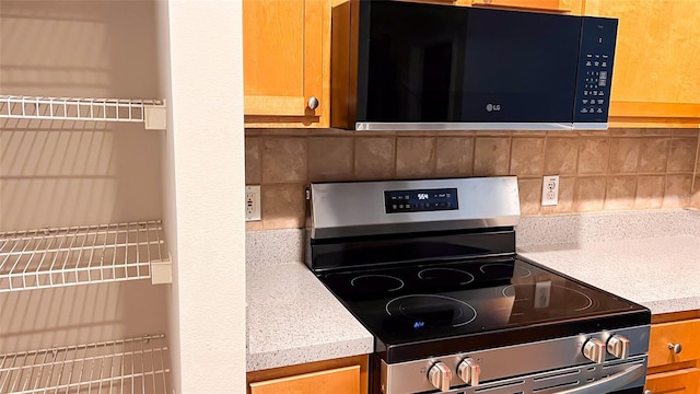 kitchen featuring stainless steel electric stove and backsplash