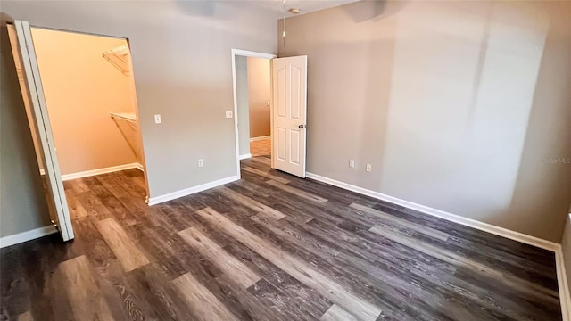 unfurnished bedroom featuring a closet, dark hardwood / wood-style floors, and a walk in closet