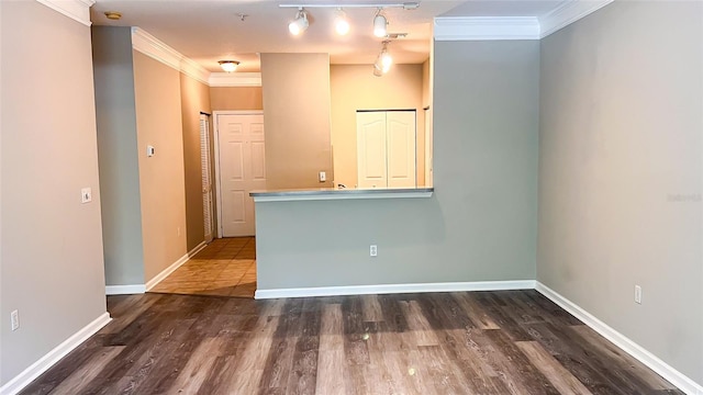 empty room with ornamental molding, track lighting, and dark hardwood / wood-style floors