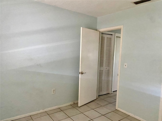 unfurnished bedroom with light tile patterned flooring and a closet