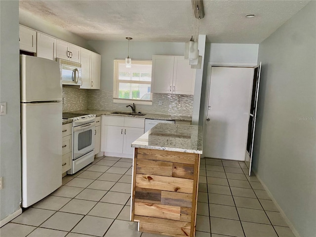 kitchen featuring white appliances, sink, pendant lighting, and white cabinets