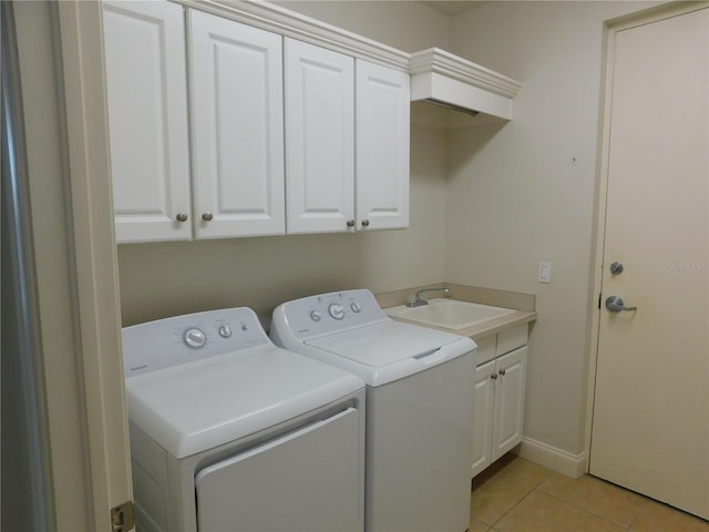 clothes washing area featuring cabinets, light tile patterned floors, washing machine and clothes dryer, and sink