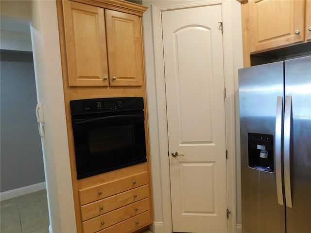 kitchen featuring light brown cabinets, black oven, stainless steel fridge, and light tile patterned floors