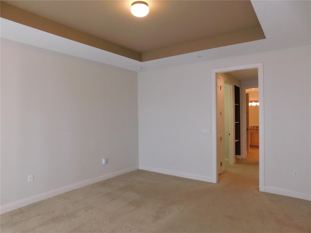 carpeted spare room featuring a tray ceiling