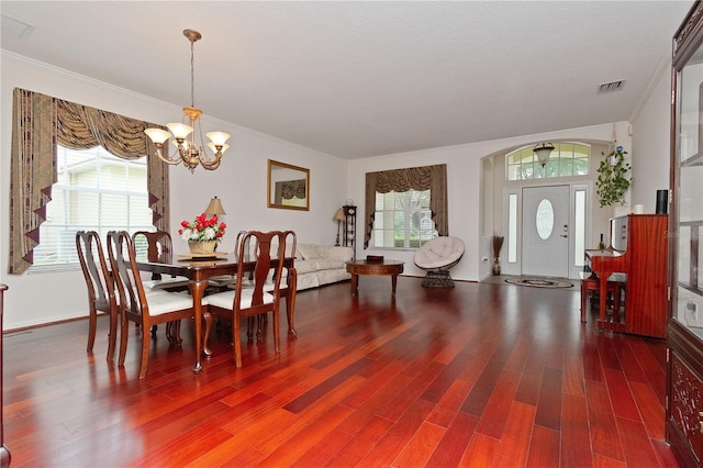 dining space with ornamental molding, dark wood-type flooring, a textured ceiling, and a chandelier