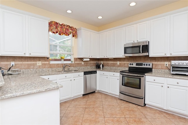 kitchen featuring light stone countertops, appliances with stainless steel finishes, sink, and white cabinets