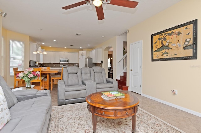 living room featuring light tile patterned flooring and ceiling fan with notable chandelier