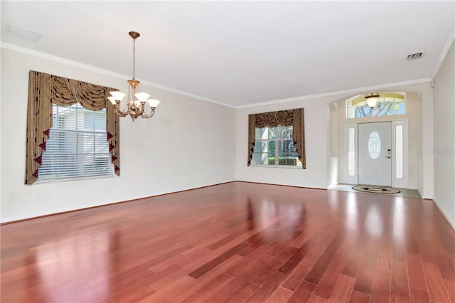 entryway featuring hardwood / wood-style flooring, ornamental molding, plenty of natural light, and a chandelier