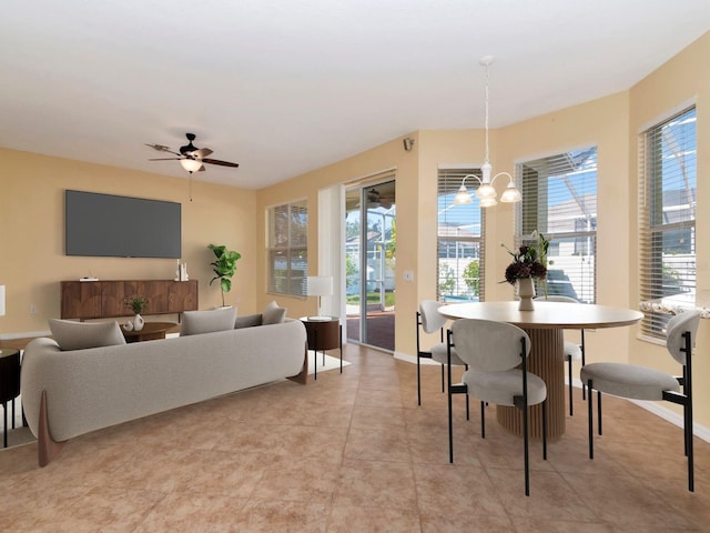 tiled dining room with ceiling fan with notable chandelier and a healthy amount of sunlight