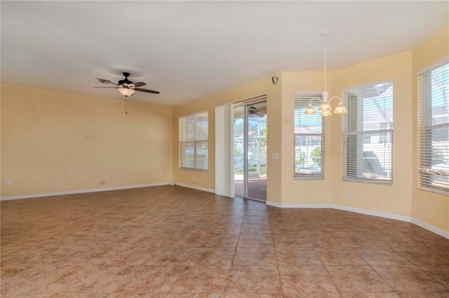 tiled spare room with ceiling fan with notable chandelier