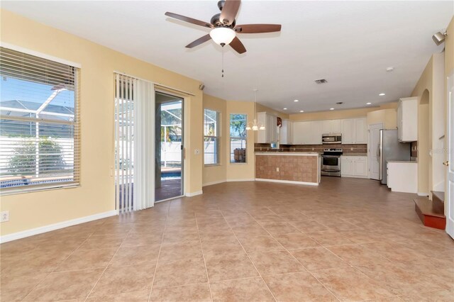 unfurnished living room with a wealth of natural light, ceiling fan, and light tile patterned floors