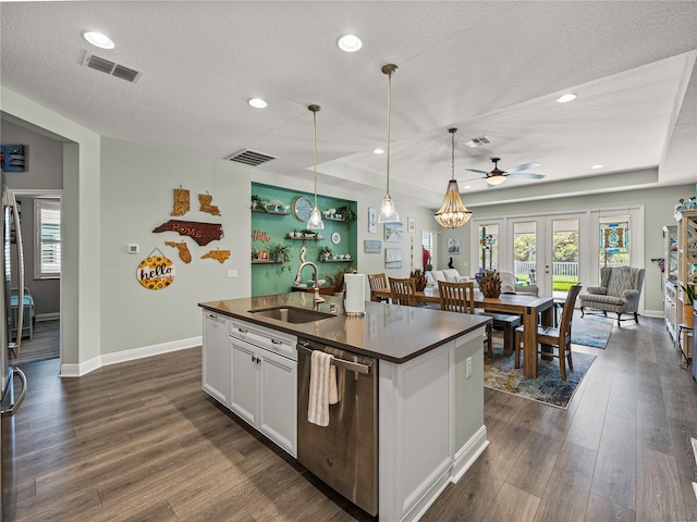 kitchen featuring hanging light fixtures, dark hardwood / wood-style flooring, an island with sink, white cabinetry, and stainless steel dishwasher