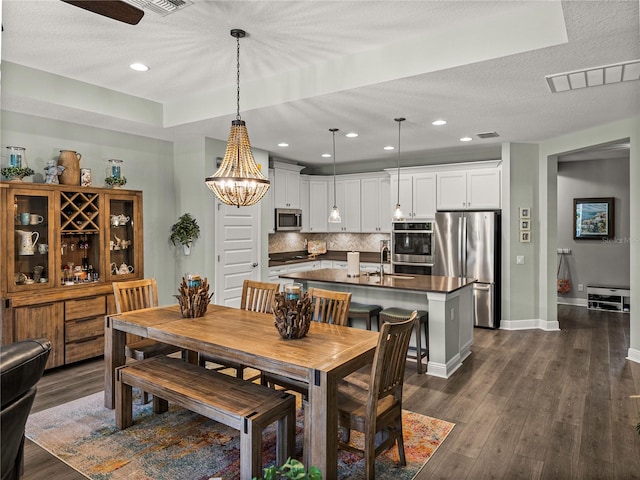 dining room featuring sink, a textured ceiling, and dark hardwood / wood-style floors