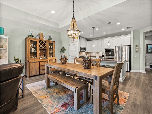 dining space with a notable chandelier, a textured ceiling, and dark hardwood / wood-style flooring