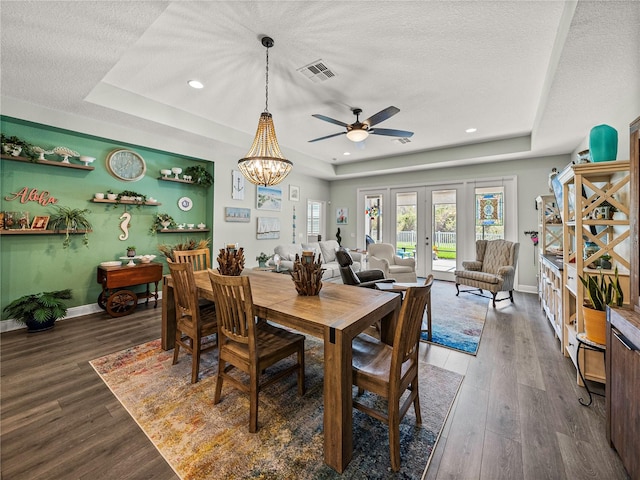 dining room with dark hardwood / wood-style floors, a textured ceiling, a tray ceiling, and ceiling fan with notable chandelier