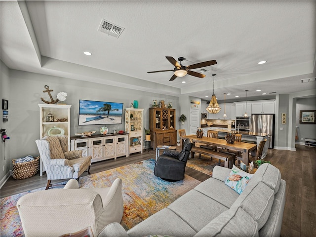 living room featuring ceiling fan, a textured ceiling, and dark hardwood / wood-style flooring