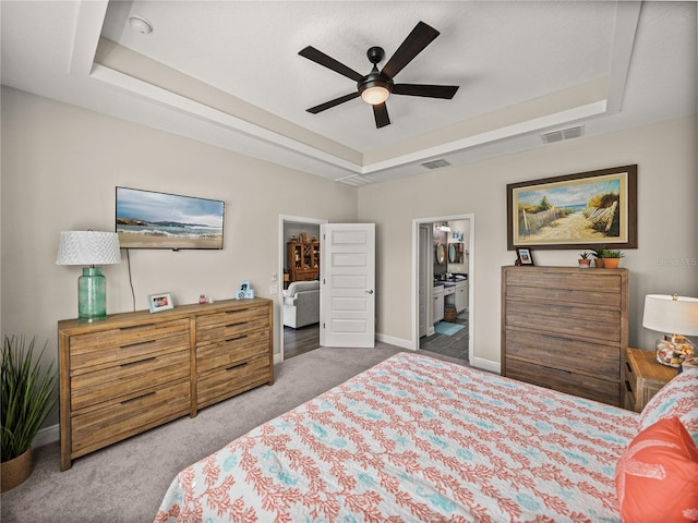 carpeted bedroom with a spacious closet, ensuite bath, a raised ceiling, and ceiling fan