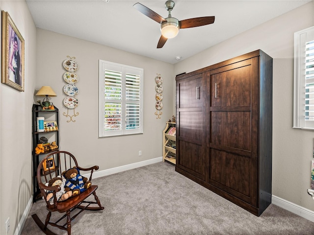 living area featuring light colored carpet and ceiling fan