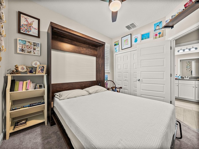 carpeted bedroom with ensuite bath, sink, a closet, and ceiling fan