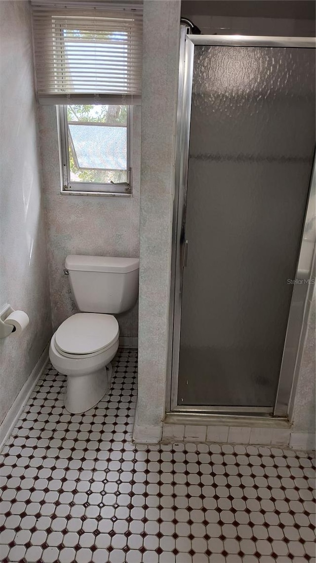 bathroom with a shower with door and toilet