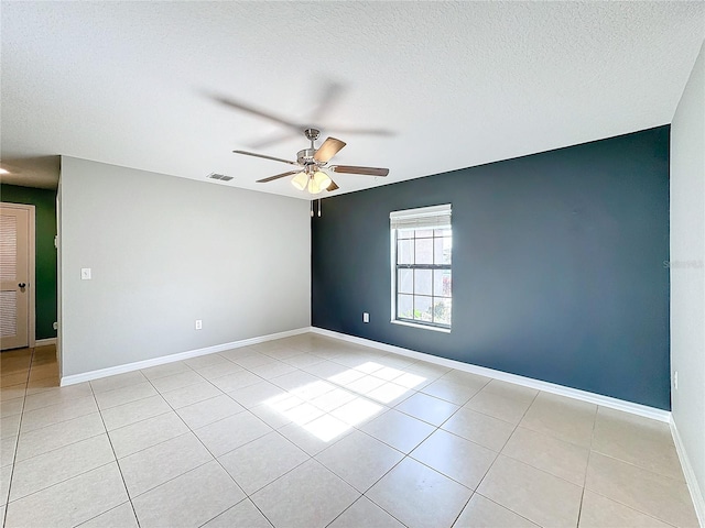 empty room with ceiling fan, a textured ceiling, and light tile patterned floors