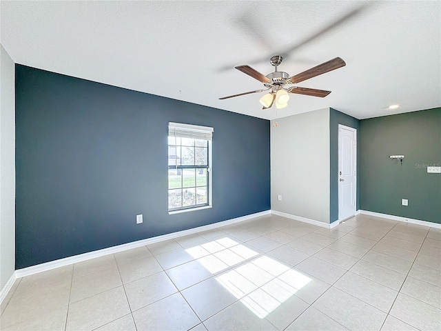 empty room with a textured ceiling, ceiling fan, and light tile patterned floors