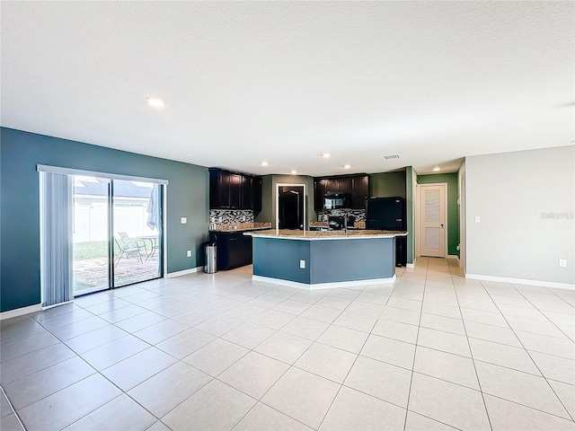 kitchen with black appliances, tasteful backsplash, light tile patterned floors, and a center island with sink