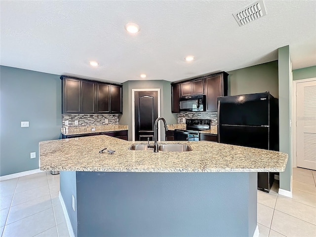 kitchen featuring a center island with sink, sink, black appliances, and decorative backsplash