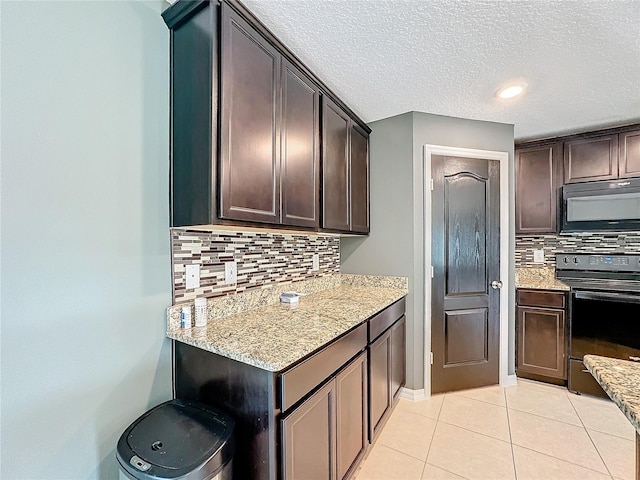 kitchen featuring dark brown cabinetry, black appliances, light stone counters, and backsplash