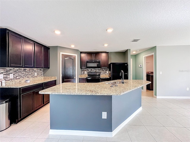 kitchen with black appliances, sink, decorative backsplash, and a center island with sink