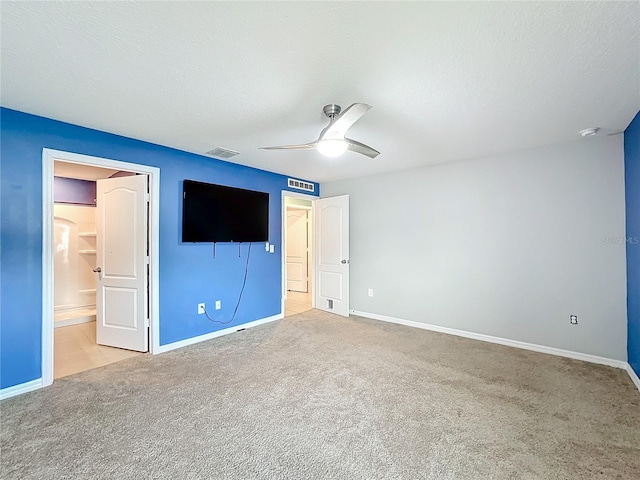 unfurnished bedroom featuring connected bathroom, a textured ceiling, light colored carpet, and ceiling fan