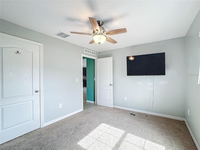 unfurnished bedroom featuring ceiling fan, a textured ceiling, and light carpet