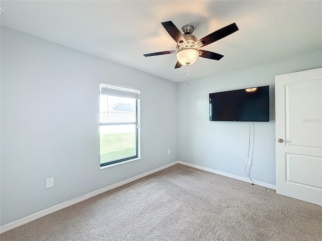 carpeted empty room featuring ceiling fan and a textured ceiling