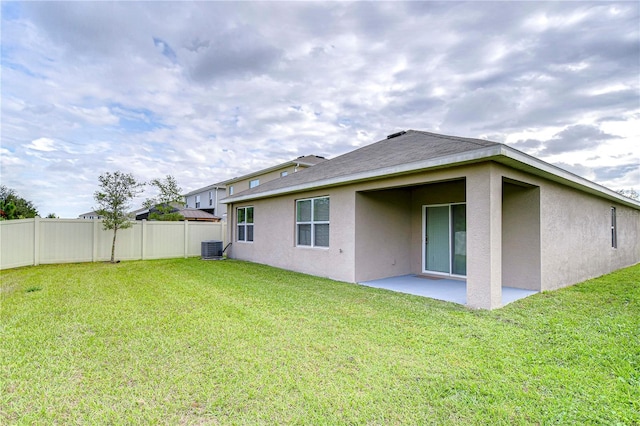 rear view of house with a lawn, central AC unit, and a patio