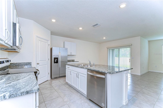 kitchen with light stone countertops, sink, a center island with sink, white cabinets, and appliances with stainless steel finishes