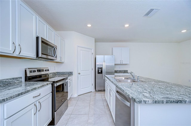 kitchen featuring appliances with stainless steel finishes, a kitchen island with sink, sink, white cabinetry, and light tile patterned flooring