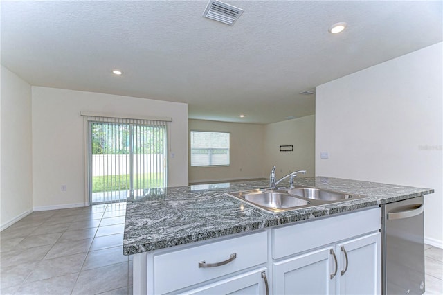 kitchen featuring a textured ceiling, a kitchen island with sink, sink, white cabinetry, and light tile patterned flooring