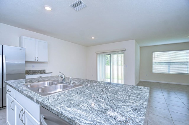 kitchen with white cabinetry, sink, stainless steel appliances, a center island with sink, and light tile patterned floors