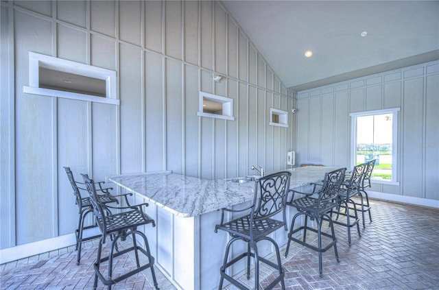 interior space featuring a kitchen breakfast bar, a center island, light stone counters, and lofted ceiling