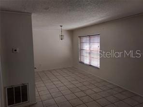 spare room featuring a textured ceiling and tile patterned flooring