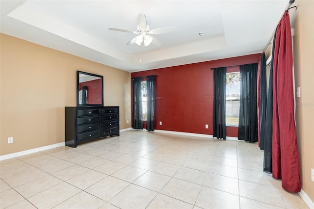 bedroom featuring light tile patterned floors, a tray ceiling, and ceiling fan